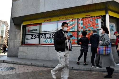 ▲2月21日，在日本东京，路人走过街边的电子股指信息显示屏。新华社/法新