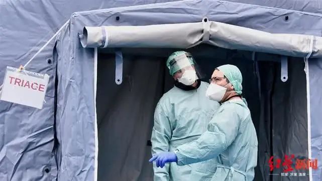 ▲意大利布雷西亚Spedali Civili医院门口，戴着防护口罩的医务工作者在医疗检查站前等待。图据路透社