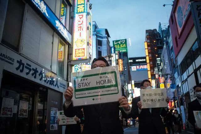 东京市政府工作人员举着牌子劝告人们待在家里。 新华社/西霸