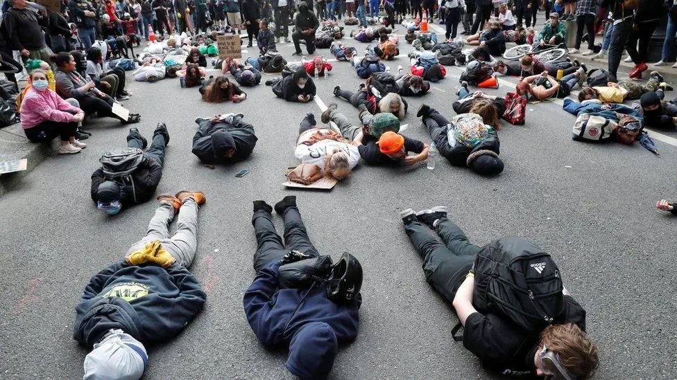 ▲当地时间5月27日，美国波特兰，示威者以弗洛伊德生前最后9分钟的姿势伏地抗议。图据BBC