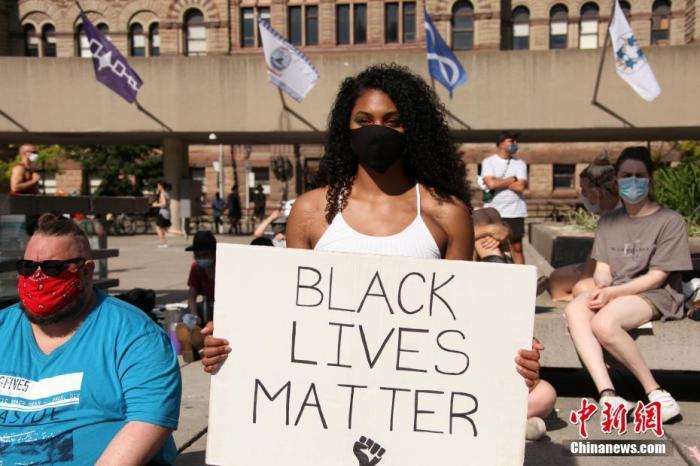 当地时间6月28日，一名非裔示威者在加拿大多伦多市政厅广场参加集会时，手举写有“黑人的命也是命”的标语牌。