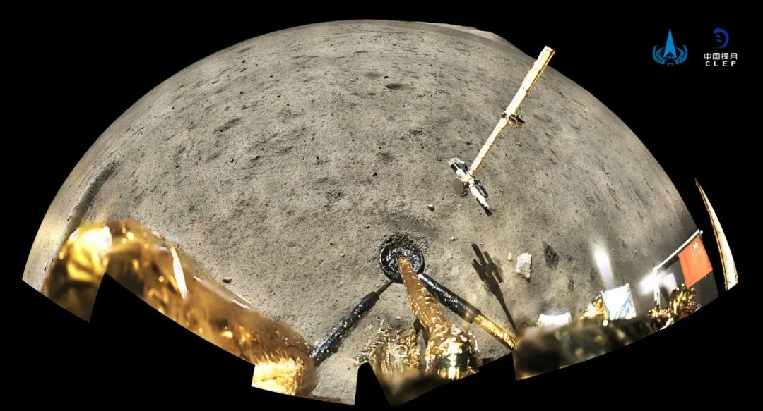 嫦娥五号着陆器和上升器组合体全景相机环拍成像，五星红旗在月面成功展开，此外图像上方可见已完成表取采样的机械臂及采样器。