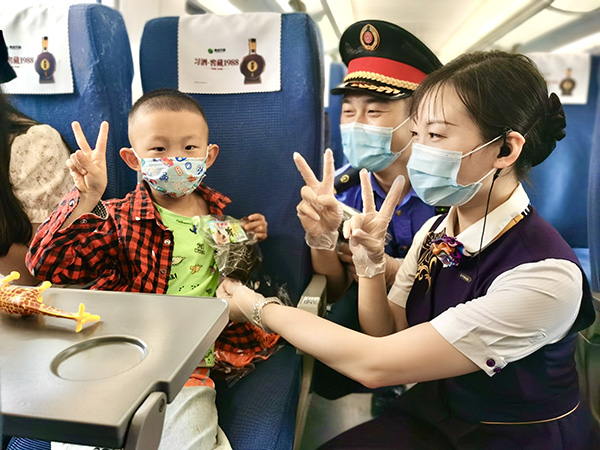 G7266次列车，乘务人员在车厢内为旅客系上红绳、送上粽子。