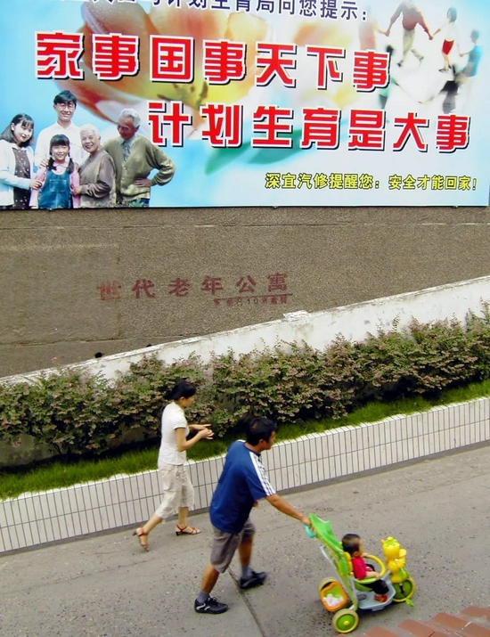 中国实行计划生育政策以来，全国已累计有近1亿独生子女。图为湖北宜昌市街头，一位父亲带着孩子从计划生育广告前经过。